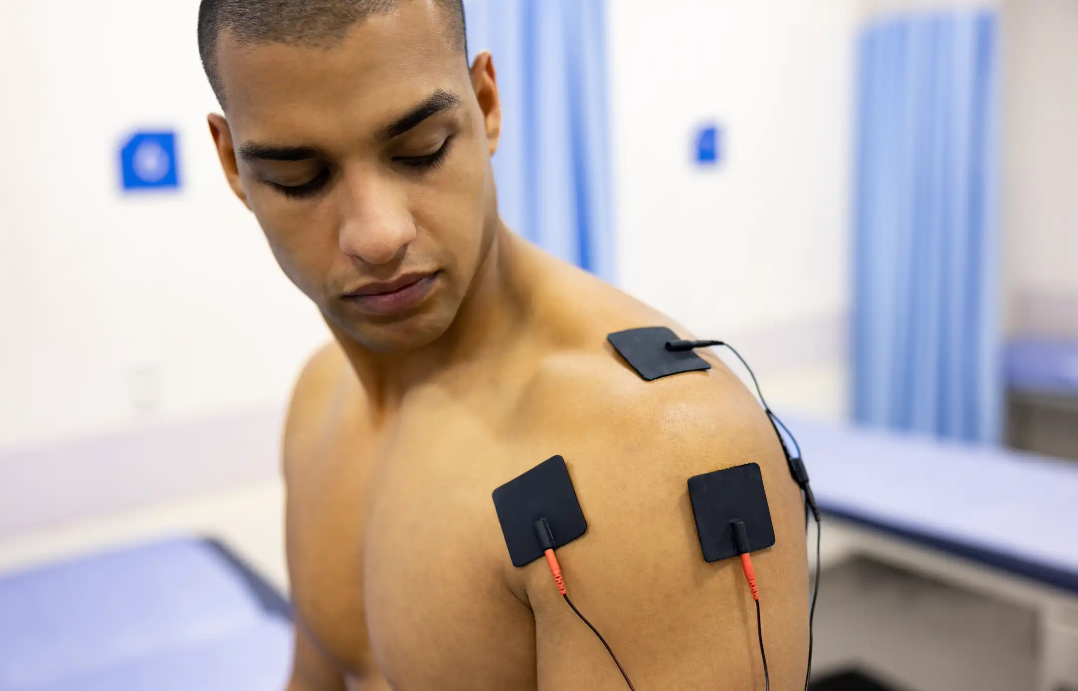 Man in physiotherapy getting electrical stimulation therapy on his shoulder